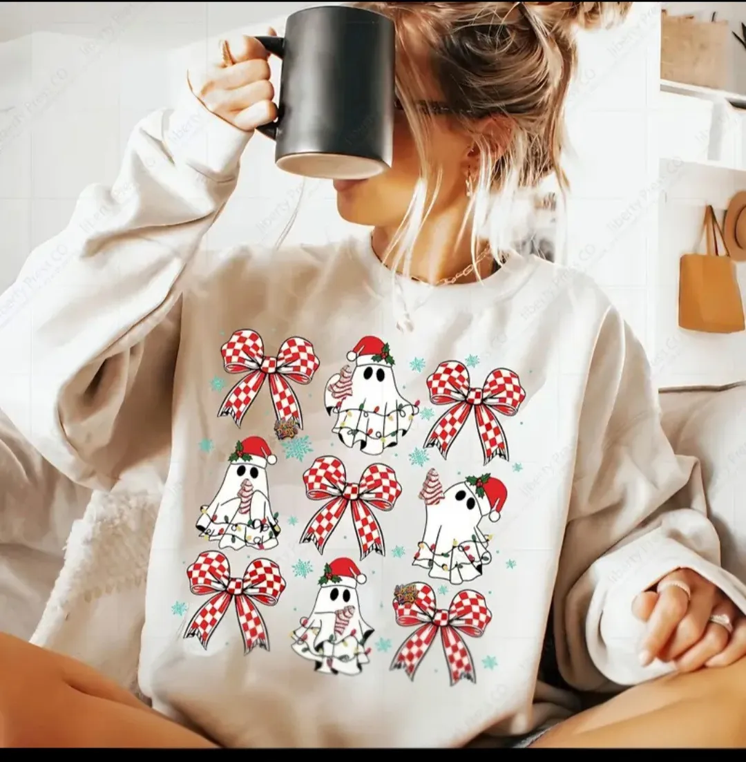 Woman wearing a white sweatshirt with ghost and red bow designs